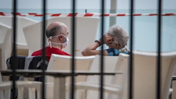 <p>Ein Paar sitzt mit Mundschutz am Swimmingpool des Hotels H10 Costa Adeje Palace. Das Hotel wurde wegen Coronavirus-Fällen unter Quarantäne gestellt.</p>