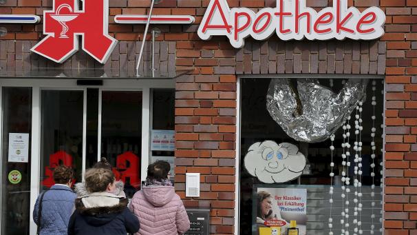 <p>Menschen warten vor einer Apotheke, bei der nur durch den Nachtschalter bedient wird. Immer mehr Menschen im Kreis Heinsberg müssen vorsorglich zu Hause bleiben.</p>