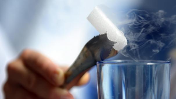 <p>Eine Hand hält eine Eiszange mit einem Trockeneiswürfel.</p>