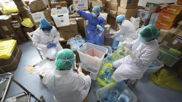 <p>Krankenschwestern montieren Gesichtsmasken in einem Krankenhaus in Wuhan für Patienten, die sich mit dem Coronavirus infiziert haben.</p>