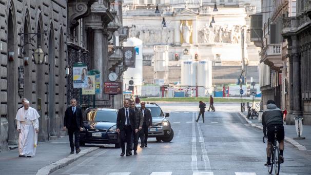 <p>Papst Franziskus (l.) geht in Begleitung von Sicherheitspersonal auf der nahezu menschenleeren Via del Corso im Zentrum der Stadt.</p>