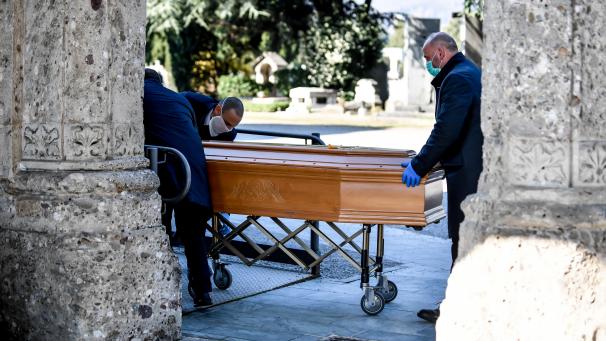 <p>Italien, Bergamo: Mitarbeiter eines Bestattungsunternehmens schieben einen Sarg. In der norditalienischen Stadt wird fast alle 30 Minuten eine Beerdigung abgehalten.</p>