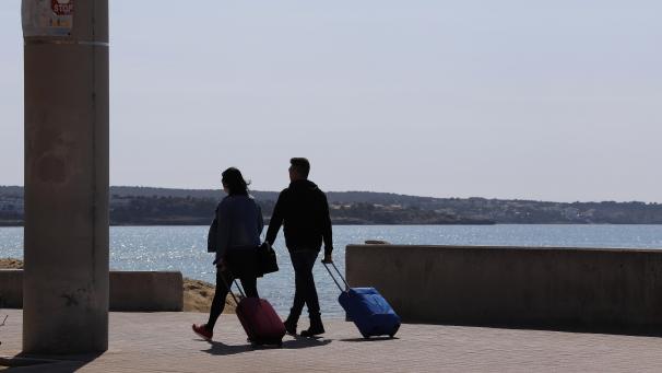 <p>Spanien, Palma: Vereinzelte Touristen ziehen am Strand von Arenal ihre Koffer.</p>