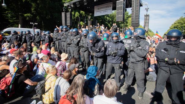 <p>1. August 2020, Berlin: Polizisten stehen bei einer Kundgebung gegen die Corona-Beschränkungen auf der Straße des 17. Juni zwischen Teilnehmern vor einer Bühne. Die Polizei hatte damals die Veranstaltung aufgelöst.</p>