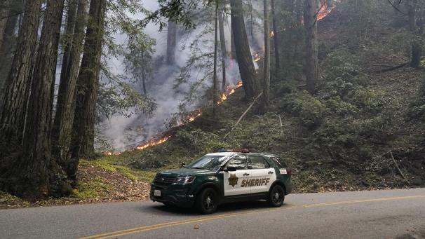 <p>Ein Polizeifahrzeug steht an einer Straße neben einem Waldbrand. Etwas kühlere Temperaturen nach einer Hitzewelle haben die Löscharbeiten der US-Feuerwehr bei den Waldbränden in Kalifornien begünstigt.</p>