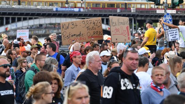 <p>Teilnehmer gehen bei einer Demonstration gegen die Corona-Maßnahmen und halten Schilder mit Parolen.</p>
