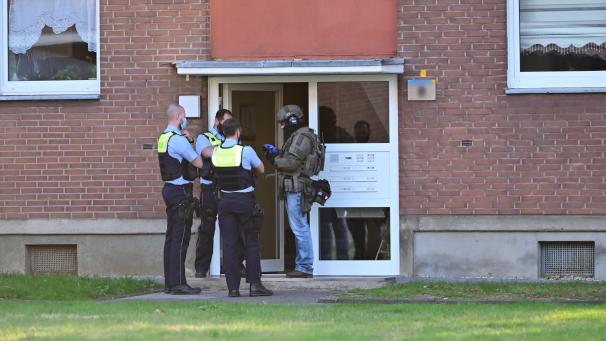 <p>Polizei und ein SEK-Beamter stehen vor der Eingangstür des Mehrfamilienhauses, in dem sich die Taten abgespielt haben.</p>