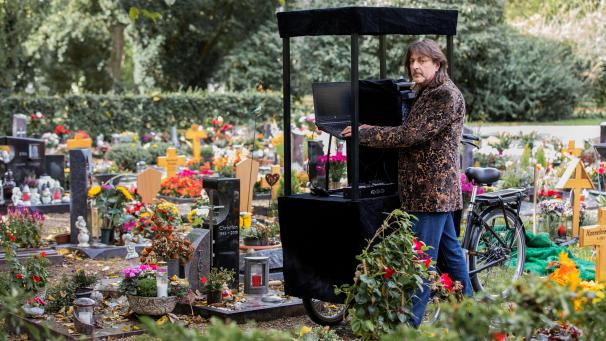<p>Theo Fitsos, Disc Jockey (DJ), steht mit seiner Musikanlage auf einem Lastenfahrrad neben einem frisch ausgehobenen Grab unmittelbar vor seinem Einsatz bei einer Beerdigung.</p>