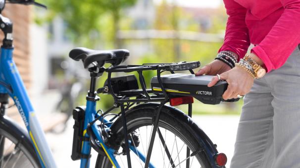 <p>Eine Frau nimmt den Akku eines E-Bikes ab.</p>