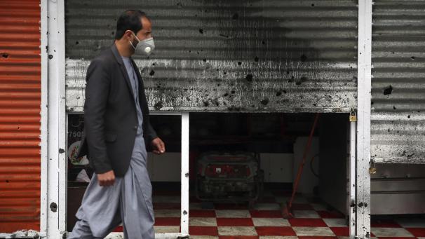 <p>Ein Mann, der aufgrund der Corona-Pandemie eine Atemschutzmaske trägt, geht in Kabul an einem durch eine Bombenexplosion beschädigten Geschäft vorbei.</p>
