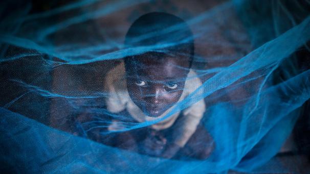 <p>Ruanda, Gashora: Ein Flüchtlingskind aus Burundi sitzt unter einem Moskitonetz gegen Malaria.</p>