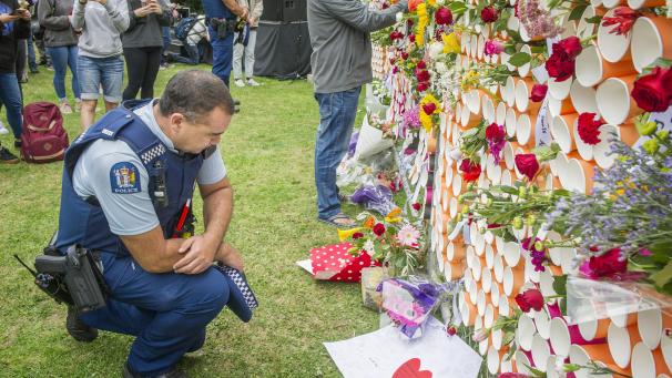 <p>Ein Polizist kniet nieder, um einige der Botschaften zu lesen, die auf einem behelfsmäßigen Denkmal für die Opfer der Anschläge von Christchurch an der University of Canterbury hinterlassen wurden.</p>