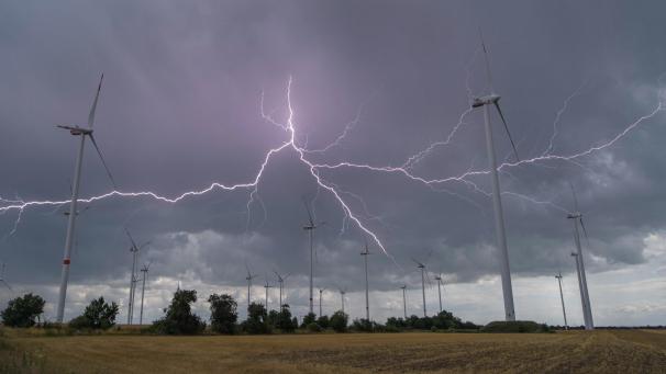 <p>Blitze eines Gewitters leuchten über Windenergieanlagen in Deutschland. Der ostbelgische Zusammenschluss „Gegenpol Ostbelgien“ warnt vor einer Verschandelung der Natur mit Windrädern.</p>