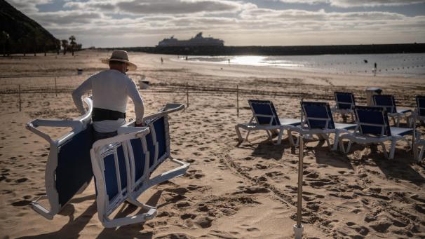 <p>Ein Tourist stellt Liegestühle am Strand von Las Teresitas in Santa Cruz de Tenerife auf.</p>
