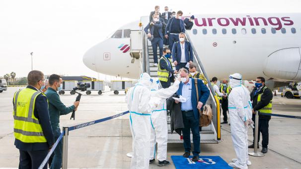 <p>Medizinisches Personal wartet in Schutzanzügen auf dem Rollfeld auf die DHB-Auswahl in Kairo.</p>