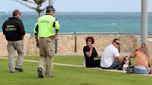 <p>Zwei Sicherheitsmänner vom Strand sprechen zu einer Gruppe von Menschen am Strand in Perth.</p>
