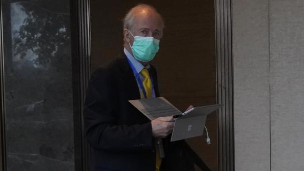 <p>Ein Mitglied des Teams der Weltgesundheitsorganisation hält einen Laptop und geht nach einem Treffen mit chinesischen Vertretern, das in einem abgesperrten Hotelbereich stattfand, einen Korridor entlang.</p>