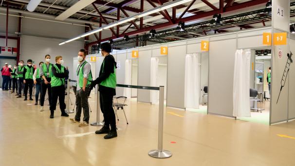 <p>Helfer warten auf Patienten in einem Impfzentrum in Berlin, das im Terminal C des ehemaligen Flughafens Tegel gelegen ist. Die beiden Impfzentren in der DG sollen im März operativ sein.</p>