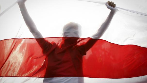 <p>Ein Demonstrant hält eine historische belarussische Fahne.</p>