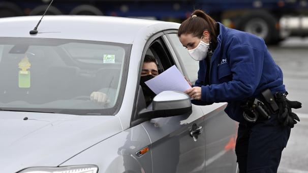 <p>Eine Polizistin überprüft die ehrenwörtliche Erklärung eines Autofahrers an der belgisch-niederländischen Grenze.</p>