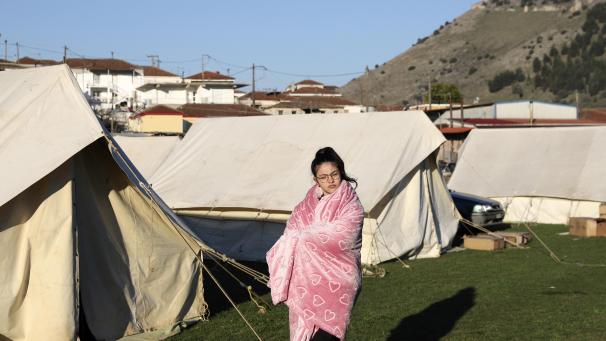 <p>Ein Mädchen steht in eine Decke gehüllt vor Zelten.</p>
