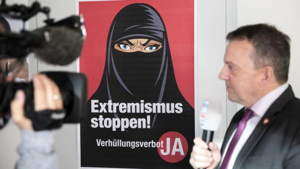 <p>Walter Wobmann, Initiator der Initiative «Ja zum Verhüllungsverbot», gibt neben einem Plakat mit der Aufschrift „Extremismus stoppen“ ein Interview.</p>