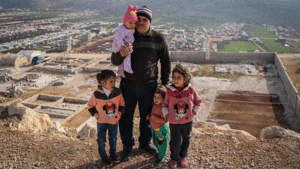 <p>Fausi Schahadat steht mit seinen vier Kindern oberhalb des Lagers, in dem sie wohnen. Fausi wurde 2018 aus dem Gouvernement Daraa vertrieben.</p>