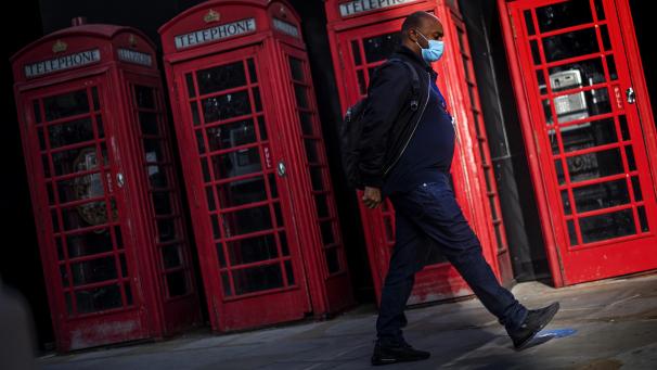 <p>Ein Mann geht in Westminster an roten Telefonzellen vorbei.</p>