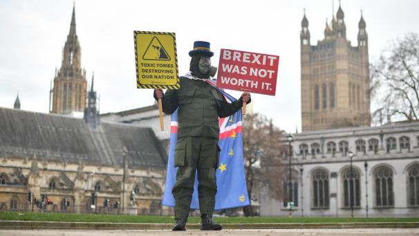 <p>Ein Anti-Brexit-Demonstrant mit Gasmaske hält auf dem Parliament Square Schilder mit den Aufschriften „Giftige Tories zerstören unser Land“ und „Brexit war es nicht wert“.</p>