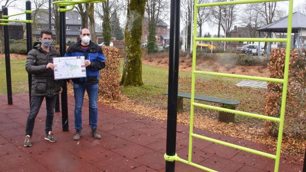 <p>Thorsten Maraite und Ralph Linden (rechts) präsentieren eine neue Dorfkarte Bütgenbachs bei widrigem Wetter am Outdoor-Fitness-Parcours des Marktplatzes.</p>