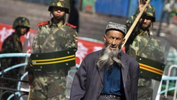 <p>Ein Angehöriger der uigurischen Minderheit in China geht in Ürümqi in der Unruheregion Xinjiang in Nordwestchina vorbei an chinesischen Sicherheitskräften.</p>