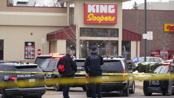 <p>Polizisten stehen am Tatort vor einem Supermarkt.</p>