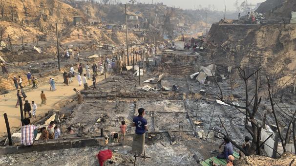 <p>Geflüchtete betrachten nach dem Brand die Überreste des Flüchtlingslager.</p>