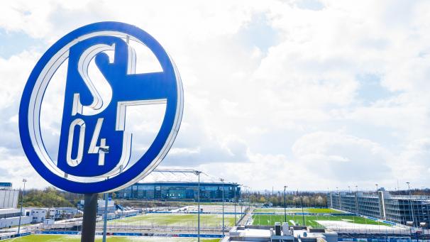 <p>Im Vordergrund dreht sich das Logo des FC Schalke auf der Geschäftsstelle; im Hintergrund steht die Veltins Arena.</p>