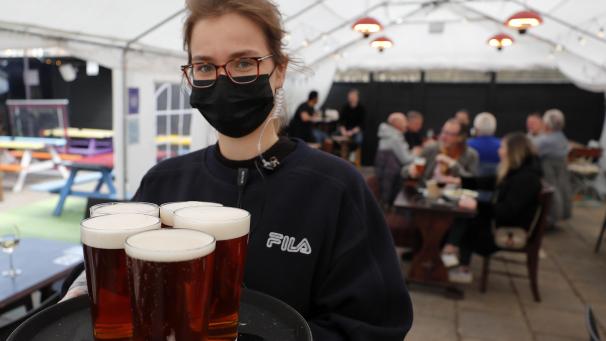 <p>Eine Kellnerin im Außenbereich des Black Lion Pubs. In England dürfen jetzt unter anderem Läden, Friseure und auch die Außengastronomie wieder aufmachen.</p>