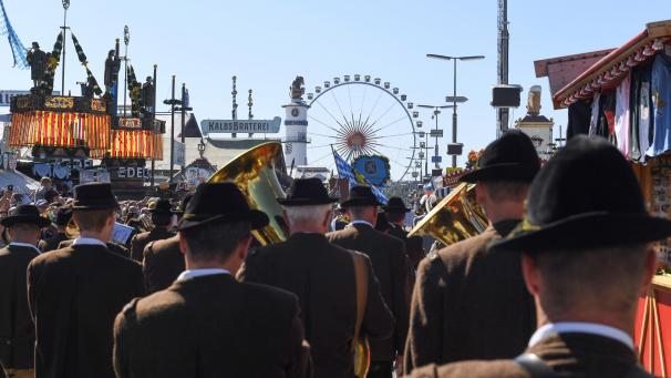 <p>Ein Schnappschuss aus dem Jahr 2019, also vor der Pandemie: Eine Blaskapelle geht beim Einzug der Festwirte über die Theresienwiese auf das Riesenrad zu.</p>