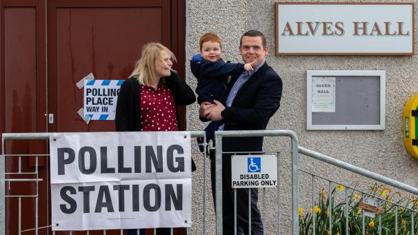 <p>Douglas Ross, Vorsitzender der Scottish Conservative Partei, kommt zusammen mit seiner Frau Krystle und seinem Sohn Alistair zur Stimmenabgabe im Wahllokal in der Alves Hall an.</p>