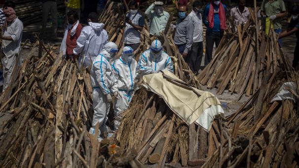 <p>Menschen in Indien vollziehen Rituale neben einem Scheiterhaufen für ein Familienmitglied, das an Covid-19 gestorben ist.</p>