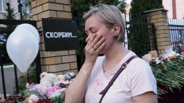 <p>Eine Frau steht nach einem Attentat vor einer russischen Schule und hält sich die Hand vor den Mund.</p>