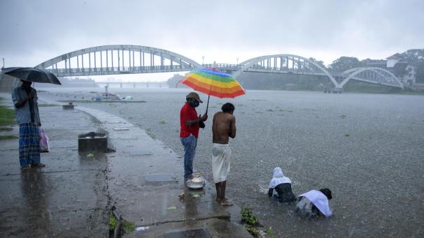 <p>Angehörige einer verstorbenen Person vollziehen Rituale im Fluss Periyar bei anhaltendem Regen.</p>