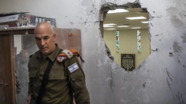 <p>Ein Sicherheitsbeamter untersucht eine zerstörte Wand in einer Synagoge, die von einer aus dem Gazastreifen abgefeuerten Rakete getroffen wurde.</p>
