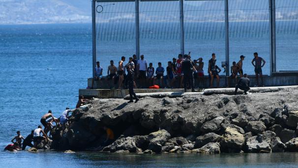 <p>Polizisten überwachen Mitgranten aus Marokko, die über den See in der Nähe des Zauns von Ceuta an Land gekommen sind.</p>