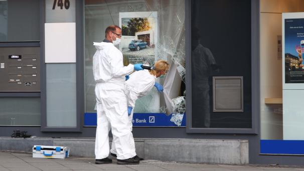 <p>Polizisten untersuchen eine beschädigte Filiale einer Bank in Aachen nach einer versuchten Geldautomatensprengung.</p>