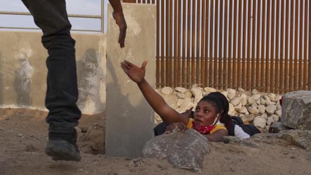 <p>Ein haitianisches Migrantenfamilienmitglied streckt die Hand nach Hilfe aus, während es aus einem felsigen Kanal neben einer Lücke in der US-Grenzmauer an der der mexikanischen Grenze heraus klettert.</p>