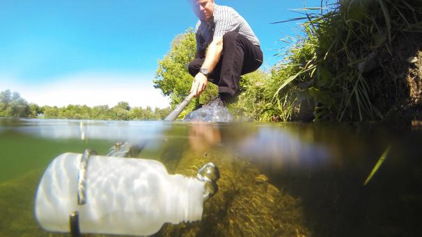<p>In einem Fluss wird eine Wasserprobe entnommen.</p>
