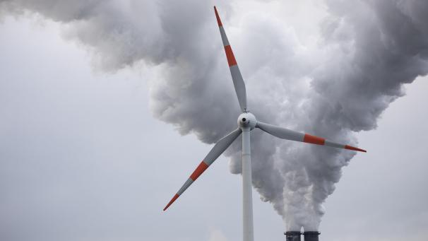 <p>Abluft steigt aus den Schornsteinen eines Kohlekraftwerks hinter einem Windrad in den Himmel.</p>