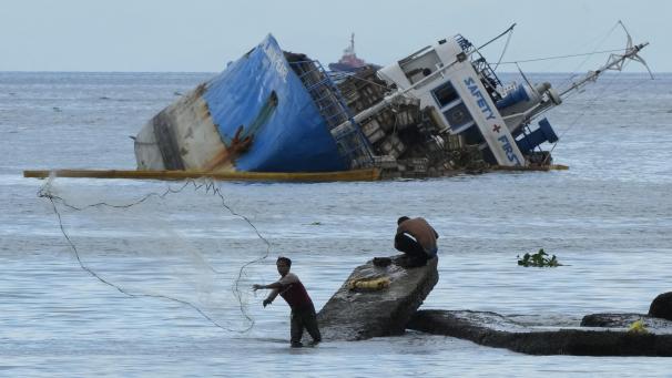 <p>Ein Fischer wirft sein Netz neben der halb gesunkenen Frachtschiff MV Palawan Pearl aus.</p>