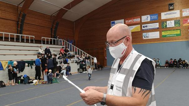 <p>Im Hintergrund warten Menschen, deren Straße evakuiert wurden. Hubert Becker vom ÖSHZ koordiniert die Helfer.</p>