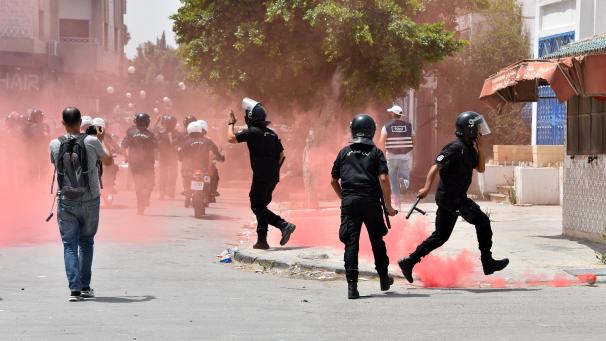 <p>Tunesische Sicherheitskräfte werden von rotem Rauch eingehüllt, der von Demonstranten während einer Kundgebung gegen die Ennahdha-Partei und die Regierung vor dem Parlament geworfen wurde. Tunesiens Präsident Kais Saied hat Ministerpräsident Hichem Mechichi in einem überraschenden Schritt seines Amtes enthoben und die Arbeit des Parlaments vorerst ausgesetzt.</p>