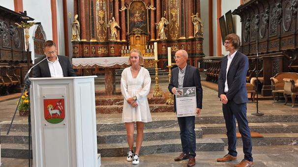 <p>Überreichung des EVBK-Förderpreises an Floriane Soltysiak durch Kreissparkassen-Vorstand Mark Kaffenberger in der St. Salvator-Basilika – rechts neben der Preisträgerin der 1. Vorsitzende der EVBK Gerald Kessler</p>